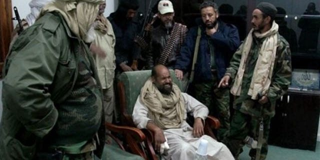 November 22, 2011: In this image taken from new video which has become available showing of Muammar Qaddafi's son Seif al-Islam, sitting at centre, wincing in pain from his injured fingers, in video taken shortly after his capture on Nov. 19, 2011, at a safe house in the town of Zintan, Libya.