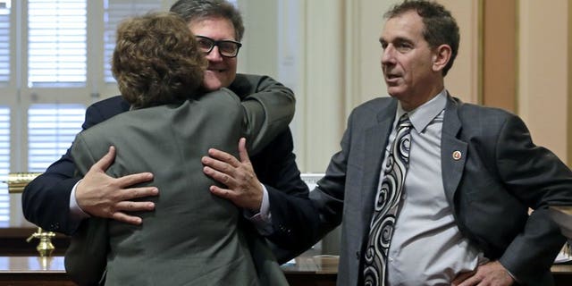 Hertzberg hugs state Sen. Lois Wolk, D-Davis, as Sen. Bob Wieckowski, D-Fremont, looks on at the Capitol in Sacramento, Calif., April 30, 2015.
