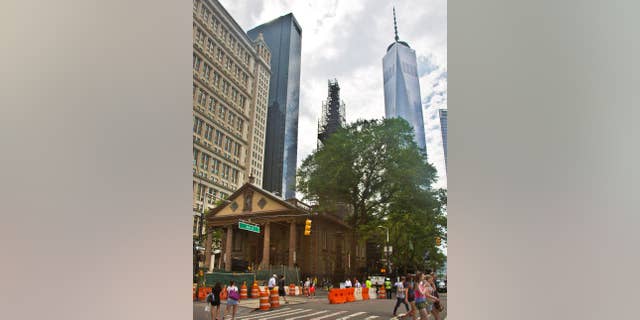 FILE - In this June 25, 2015, file photo, the World Trade Center, right, looms behind St. Paul's Chapel with its steeple wrapped in scaffolding for repairs, in New York. The winner of a new competition open to people of all faiths called "The Reconciliation Preaching Prize," has been won by an Army chaplain from Austin, Texas. The Rev. David Peters will have the privilege of delivering an original sermon on Sept. 11, at the chapel near ground zero that was turned into a makeshift memorial shrine and became a place of rest and renewal for volunteers and responders, following the terrorist attacks that brought down the twin towers. (AP Photo/Bebeto Matthews, File)
