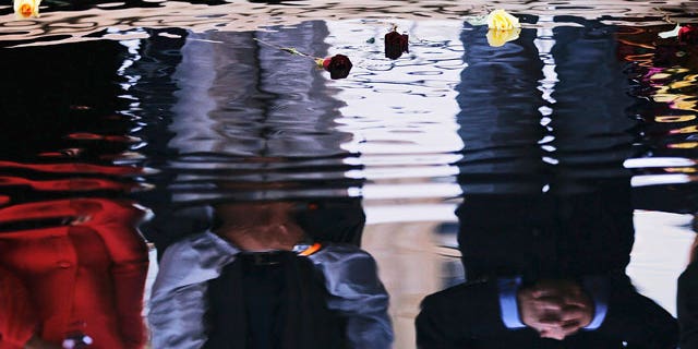 Flowers float in a reflecting pool in memory of victims of the Sept. 11 terrorist attacks after politicians dropped them into the water during the ninth anniversary of the attacks at the World Trade Center Saturday, Sept. 11, 2010 in New York.
