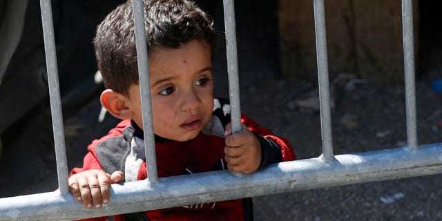 Aug. 24, 2015: A migrant boy looks through fence in a migrant processing center in the southern Serbian town of Presevo. (AP Photo/Darko Vojinovic)