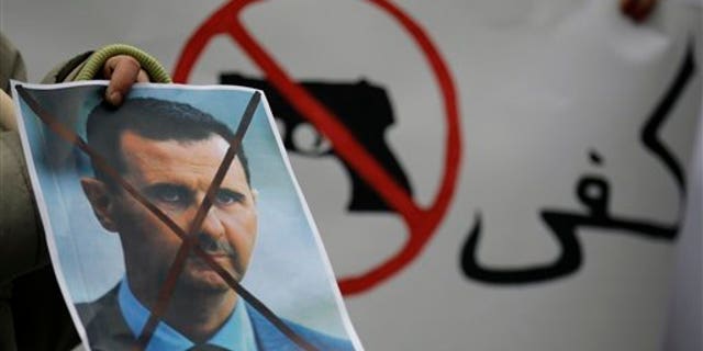 Dec. 23: A Syrian immigrant holds a crossed out depiction of Syrian President Bashar al-Assad during a rally against his regime in front of the Syrian embassy in Belgrade, Serbia.