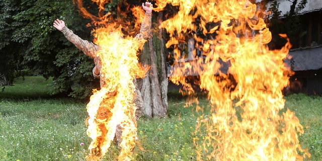 An officer on duty attempts to knock down the flame as former Ukrainian serviceman Serhii Ulianov sets himself on fire.