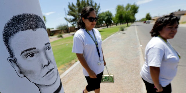 FILE--In this July 27, 2016, file photo, Phoenix neighborhood patrol officers Maribel Diaz Lopez, left, and Mario Ocampo walk Maryvale neighborhood streets in Phoenix, Ariz., to hand out an artist rendering of a suspected serial killer, as shown on the light pole, and block watch flyers. Authorities have released police reports on two of seven shooting deaths that investigators believed were carried out by a serial killer. The reports detail the shooting deaths of Manual Castro Garcia and Horacio de Jesus Pena, who died a week apart in June in the city's Maryvale neighborhood. (AP Photo/Matt York, file)