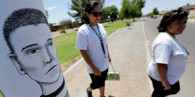 FILE--In this July 27, 2016, file photo, Phoenix neighborhood patrol officers Maribel Diaz Lopez, left, and Mario Ocampo walk Maryvale neighborhood streets in Phoenix, Ariz., to hand out an artist rendering of a suspected serial killer, as shown on the light pole, and block watch flyers. Authorities have released police reports on two of seven shooting deaths that investigators believed were carried out by a serial killer. The reports detail the shooting deaths of Manual Castro Garcia and Horacio de Jesus Pena, who died a week apart in June in the city's Maryvale neighborhood. (AP Photo/Matt York, file)