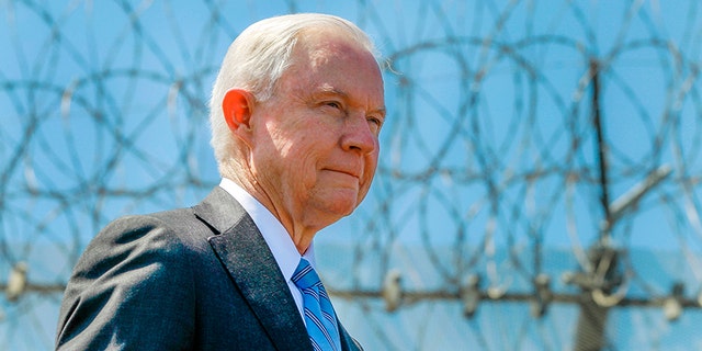 In April 21, 2017, file photo, Attorney General Jeff Sessions stands near a secondary border fence during a news conference at the U.S.-Mexican border next to the Brown Field Border Patrol Station in San Diego.
