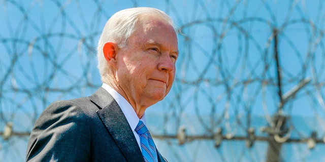 In April 21, 2017, file photo, Attorney General Jeff Sessions stands near a secondary border fence during a news conference at the U.S.-Mexican border next to the Brown Field Border Patrol Station in San Diego.