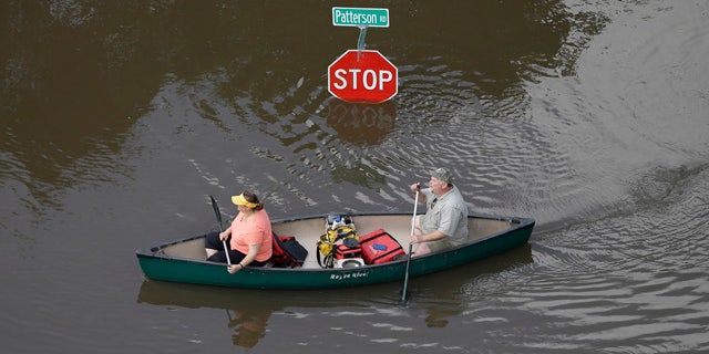 May 30, 2015: In this aerial photo, people canoe through floodwaters past a stop sign near Bear Creek Park in Houston. (AP Photo/David J. Phillip)