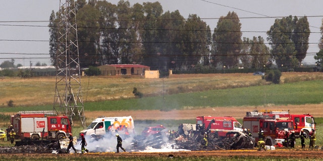 Emergency services personnel work in the area after a plane crash near the Seville airport, in Spain, Saturday, May 9, 2015. A military transport plane crashed near southwestern Seville airport Saturday, killing its crew, Spain's prime minister said. It is unclear if any others were injured. Mariano Rajoy said up to 10 crew members were aboard the brand new Airbus A400M aircraft that was undergoing flight trials at the airport. (AP Photo/Miguel Angel Morenatti)