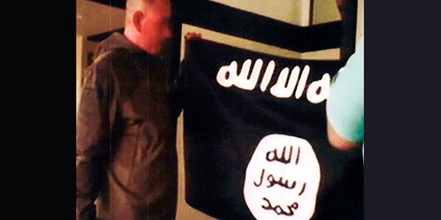 Army Sgt. 1st Class Ikaika Kang holds an Islamic State group flag after allegedly pledging allegiance to the terror group at a house in Honolulu on July 8, 2017. Kang plead guilty Wednesday, as charged in an indictment last year. He is agreeing to a 25-year sentence for charges that could have put him in prison for life.
