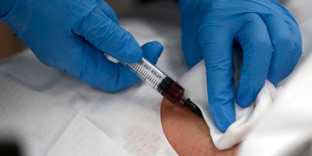 A doctor draws blood from the neck of a patient at an emergency room of a hospital in Shanghai May 15, 2013. To match CHINA-HOSPITALS/BRIBERY Picture taken May 15, 2013. REUTERS/Aly Song (CHINA - Tags: HEALTH CRIME LAW BUSINESS) - RTX11WJN