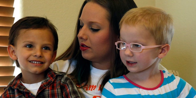 In this April 29, 2014 photo, mother of a child with cancer Sierra Riddle plays with her son Landon, age 4, left, and Landon's friend Dahlia, age 3, who also has cancer, during a play date at Dahlia's home in Colorado Springs. Landon and Dahlia's parents, frustrated with mainstream medical treatments and facing the possibility of intervention by child protective authorities, moved to Colorado to treat their children using what some describe as cutting edge cannabis medication. Hundreds of parents in similar situations find themselves at the center of a debate about how far government can and should reach when parents push against legal boundaries to save their childrens' lives.