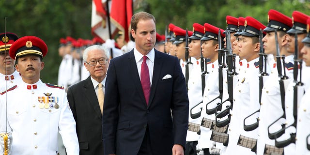 Prince William, the Duke of Cambridge, center, is accompanied by Singapore's President Tony Tan, as he inspects an honor guard during the welcome ceremony at the Istana, or Presidential Palace, on Tuesday Sept. 11, 2012 in Singapore. The Duke and Duchess of Cambridge started an official three-day trip to Singapore Tuesday. (AP Photo/Wong Maye-E)