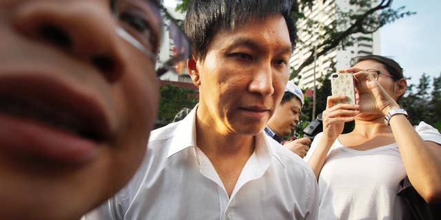 In this July 12, 2012, file photo, City Harvest Church founder Kong Hee, center, is surrounded by the media as he arrives at the Subordinate Courts in Singapore. The founder of the popular Singapore church has been found guilty Wednesday, Oct. 21, 2015, of misappropriating about $35 million in donations to support his wife's singing career in Asia before helping her break into the U.S. market for evangelization purposes. (AP Photo/Wong Maye-E, File)