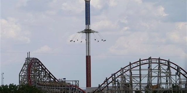July 20, 2013: The Texas Giant roller coaster ride sits idle in the foreground as people take in another ride a the Six Flags Over Texas park Saturday in Arlington, Texas.