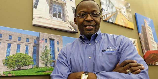 Mel Gravely, president of TriVersity Construction, poses in his office in front of some paintings of work his company has done, Wednesday, April 16, 2014, in Cincinnati. Gravely’s company joined a program called a minority business accelerator even before he bought a controlling interest in the Cincinnati-based company in 2006. It helped the company get started and win contracts that have helped Triversity’s revenue double. (AP Photo/Al Behrman)