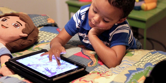 Frankie Thevenot, 3, plays with an iPad in his bedroom at his home in Metairie, La.  As of Wednesday, Aug. 7, 2013, the Campaign for a Commercial-Free Childhood, is urging federal investigators to examine the marketing practices of Fisher-Price's and Open Solution's mobile apps. It's the campaign's first complaint against the mobile app industry.