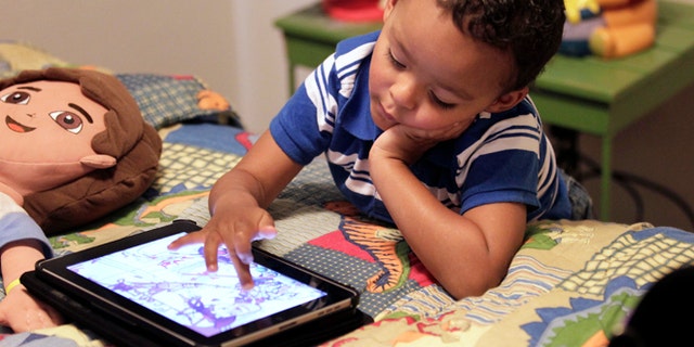 Frankie Thevenot, 3, plays with an iPad in his bedroom at his home in Metairie, La. As of Wednesday, Aug. 7, 2013, the Campaign for a Commercial-Free Childhood, is urging federal investigators to examine the marketing practices of Fisher-Price's and Open Solution's mobile apps. It's the campaign's first complaint against the mobile app industry.