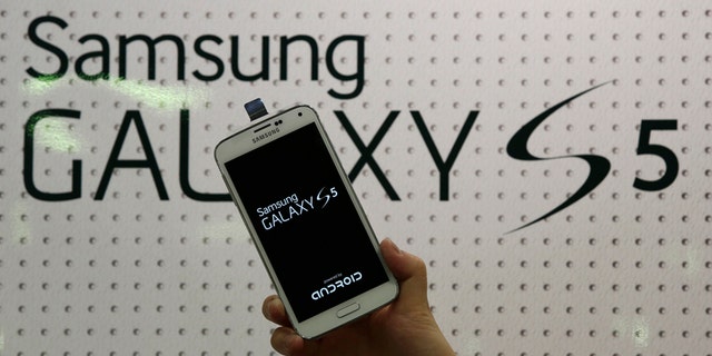 An employee shows Samsung's Galaxy S5 smartphone at a mobile phone shop in Seoul, South Korea.