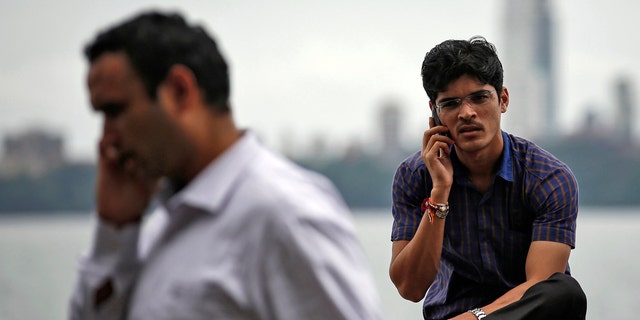 File photo - men speak on their mobile phones on a seafront in Mumbai Aug. 28, 2014.