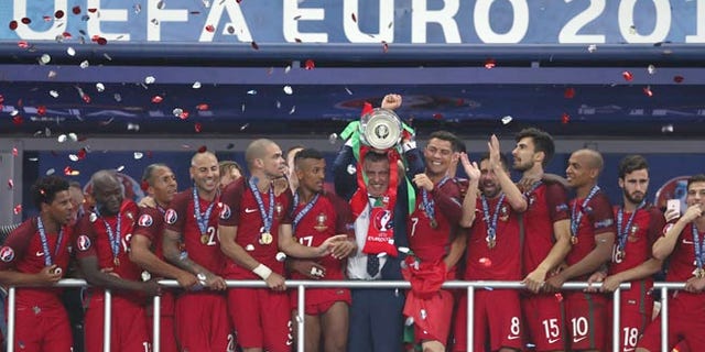 Portugal coach Fernando Santos lifts the trophy between Cristiano Ronaldo, Sunday, July 10, 2016.