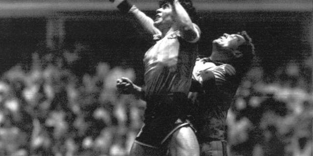 FILE - This is a Sunday, June 22, 1986 file photo of Argentina's Diego Maradona, left, as he is seen in the controversial action in which he knocked the ball with his left hand into the net of England's goalie Peter Shilton to score his team's first goal when Argentina defeated England 2-1 in the World Cup quarterfinal in the Mexico City Aztec stadium. Cheating. It's an ugly side of the beautiful game and it involves just about every aspect of it. The World Cup in Brazil begins in June and the founders of association football would shudder at how entrenched deception and trickery have become in the modern game. (AP Photo/El Grafico, File)