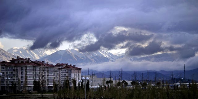 February 1, 2014: The Caucasus Mountains, site of the 2014 Winter Olympic outdoor snow sport and sliding track events, rise above a recently built housing complex, at left, near the Olympic Park by the Black Sea in the Coastal Cluster in Sochi, Russia. (AP Photo/David Goldman)