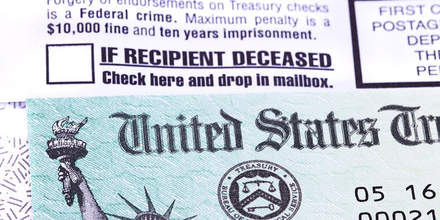 A United States government Treasury Check used to pay Social Security or Medicare benefits lies on top of the opened envelope used to mail it to the recipient. The envelope has warnings of criminal penalties for anyone who fraudulently endorses the check. It also warns that if the recipient is deceased, the check should be placed in the return mail. The distinctive green checks feature an engraving of the Statue of Liberty and the Treasury Seal.