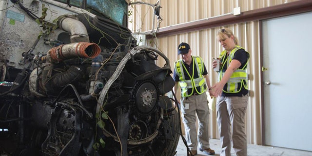 September 27, 2014: In this photo provided by The National Transportation Safety Board, officials examine part of the wreckage involved in a fatal highway accident in Davis, Okla. (AP Photo/National Transportation Safety Board)
