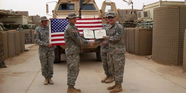 Army 1st Lt. Michael Behenna, in Iraq with some members of his platoon, before he was arrested over the shooting of an Iraqi man in his custody. In the back, right holding the U.S. flag is Adam Kohlhaas, who was killed in a roadside bombing tied to an Al Qaeda cell.