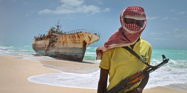 Sept. 23, 2012: In this file photo, masked Somali pirate Hassan stands near a Taiwanese fishing vessel that washed up on shore after the pirates were paid a ransom and released the crew, in the once-bustling pirate den of Hobyo, Somalia. Three Somali pirates were killed in a fight over the ransom paid to free the German-American journalist Michael Scott Moore who was released this week after two years and eight months of captivity, a Somali police official said Friday, Sept. 26, 2014.