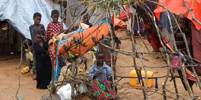 Child from southern Somalia stand near their makeshift shelter at a camp in Mogadishu, Somalia, Monday, Aug 1, 2011. Tens of thousands of famine-stricken Somali refugees were cold and drenched after torrential rains overnight pounded their makeshift structures in the capital, Mogadishu. Rains are needed to plant crops and alleviate the drought that is causing famine in Somalia but on Saturday night the rains added to the misery of refugees who live in structures made of sticks and pieces of cloth.