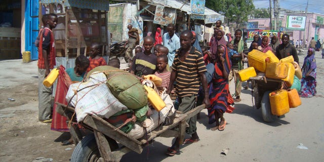 Somalis from southern Somalia carrying their belongings make their way to a new camp for internally displaced people in Mogadishu Somalia, Thursday July, 28, 2011.