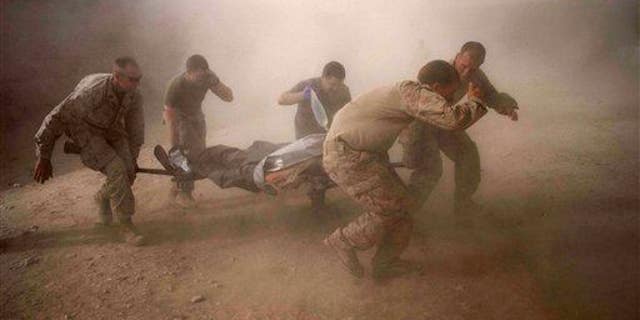 US Marines rush a colleague wounded in an IED strike in the volatile Helmand Province of southern Afghanistan on Tuesday, May 10, 2011.