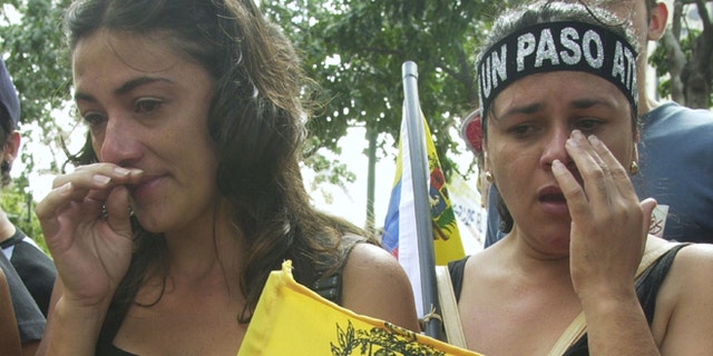 CARACAS, VENEZUELA - DECEMBER 7: Two woman cry near the site where a demonstrator was killed December 7, 2002 at Plaza Francia in Caracas, Venezuela. The demonstrator was killed December 6, 2002 when gunmen opened fire during an opposition rally killing at least three and injuring 28. (Photo by Oscar Sabetta/Getty Images)