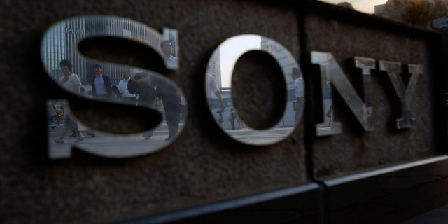 Pedestrians are reflected in a logo of Sony Corp outside its showroom in Tokyo July 16, 2014. Japan's Sony Corp is hammering out plans to rise from the ashes of nearly $10 billion lost in six years by building a future around its last consumer electronics blockbuster - the PlayStation. Sony plans to reposition the video console warhorse as a hub for a network of streamed services, according to three senior officials, offering social media, movies and music as well as games. The executives spoke to Reuters on condition they not be named because the matters are still in early stages of discussion. Picture taken July 16, 2014. REUTERS/Yuya Shino (JAPAN - Tags: BUSINESS LOGO) - RTR40G1E