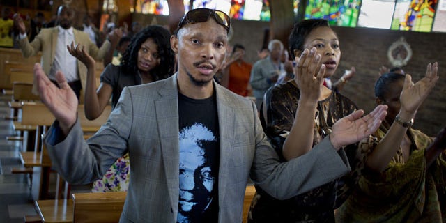 December 8, 2013: Mourners attend an early morning church service in memory of Nelson Mandela at the Regina Mundi church, which became one of the focal points of the anti-apartheid struggle, in Soweto, Johannesburg, People in South Africa are taking part in a day of "prayer and reflection" for late President Nelson Mandela. (AP Photo/Ben Curtis)