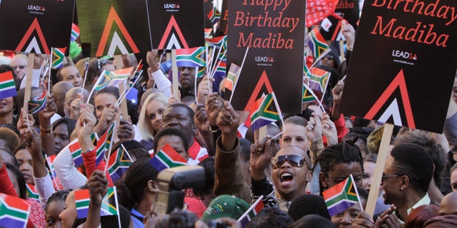 In this photo taken Friday June 1, 2012,  members of the public and celebrities gather to videotape a sing-a-long birthday wish for former president Nelson Mandela, portrait on woman's shirt, on Nelson Mandela Square in Johannesburg. Mandela's office on Monday June 18 2012 has released the video of South Africans singing "Happy Birthday" in an effort to motivate people around the world to salute the anti-apartheid icon ahead of his 94th birthday next month. (AP Photo/Denis Farrell)