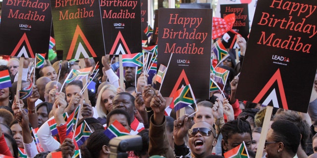 In this photo taken Friday June 1, 2012, members of the public and celebrities gather to videotape a sing-a-long birthday wish for former president Nelson Mandela, portrait on woman's shirt, on Nelson Mandela Square in Johannesburg. Mandela's office on Monday June 18 2012 has released the video of South Africans singing "Happy Birthday" in an effort to motivate people around the world to salute the anti-apartheid icon ahead of his 94th birthday next month. (AP Photo/Denis Farrell)