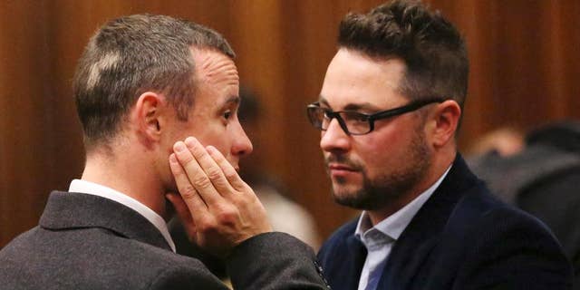 FILE - In this Tuesday May 20, 2014 file photo brother of murder accused, Oscar Pistorius, left, Carl Pistorius, right, speaks with his brother in court in Pretoria, South Africa. Aug. 1, 2014. Carl Pistorius has been discharged from an intensive care unit in the hospital after suffering internal injuries and going into respiratory failure following a car crash Aug. 1, 2014. (AP Photo/Siphiwe Sibeko, Pool, File)
