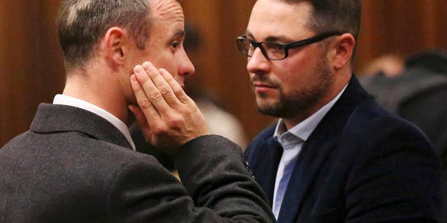 FILE - In this Tuesday May 20, 2014 file photo brother of murder accused, Oscar Pistorius, left, Carl Pistorius, right, speaks with his brother in court in Pretoria, South Africa. Aug. 1, 2014. Carl Pistorius has been discharged from an intensive care unit in the hospital after suffering internal injuries and going into respiratory failure following a car crash Aug. 1, 2014. (AP Photo/Siphiwe Sibeko, Pool, File)