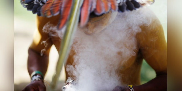 An indigenous man from the Pataxo tribe burns incense as he attends an assembly at Kari-Oca village in Rio de Janeiro.