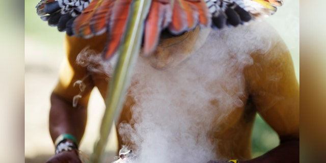 An indigenous man from the Pataxo tribe burns incense as he attends an assembly at Kari-Oca village in Rio de Janeiro.