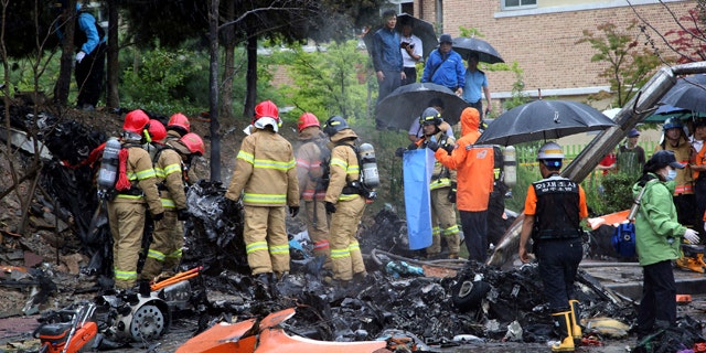 July 17, 2014: Firefighters inspect the wreckage of a helicopter which crashed near an apartment complex and school in Gwangju, South Korea. (AP Photo/Yonhap, Park Chul-hong)