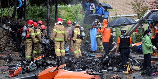 July 17, 2014: Firefighters inspect the wreckage of a helicopter which crashed near an apartment complex and school in Gwangju, South Korea. (AP Photo/Yonhap, Park Chul-hong)