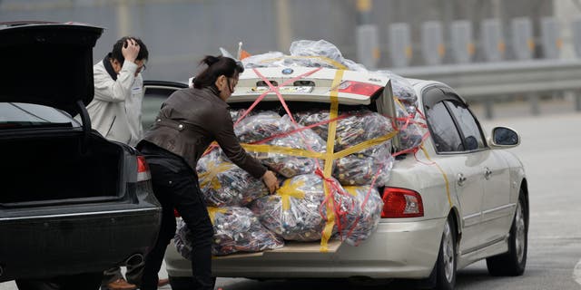 A South Korean worker, left, who arrives with electronic products from North Korea's Kaesong, is helped by a South Korean woman who greeted him, after returning from the North at the customs, immigration and quarantine office near the border village of Panmunjom, that has separated the two Koreas since the Korean War, in Paju, north of Seoul, South Korea, Monday, April 8, 2013.