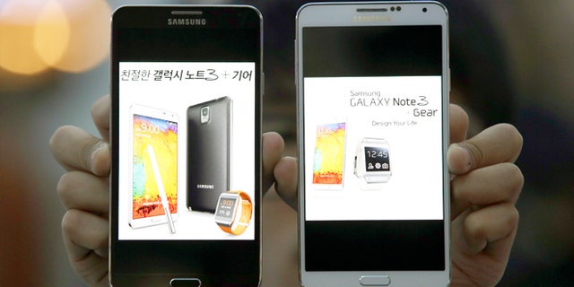 Oct. 23, 2013: An employee of Samsung Electronics holds two Galaxy Note 3 smartphones while posing for photos at a train station in Seoul, South Korea.