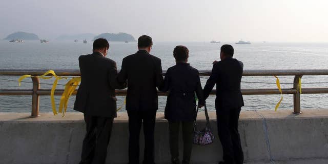 Christians pray near yellow ribbons with messages for the victims and missing passengers of the sunken ferry Sewol, at a port in Jindo, south of Seoul, South Korea, Monday, May 12, 2014. Bad weather prevented divers from searching inside the sunken, deteriorating South Korean ferry for a third day Monday. (AP Photo/Yonhap) KOREA OUT