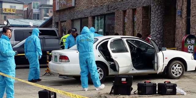 Feb. 25, 2015: South Korean police officers investigate a vehicle near the scene of an incident in Sejong, south of Seoul. South Korean police said Wednesday that three people were dead after a gunman opened fire at a store in Sejong City and set the store on fire before fleeing. (AP Photo/Yonhap, Lee Jae-lim)