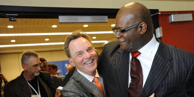 The Rev. Ronnie Floyd, center, of Cross Church in northwest Arkansas, hugs The Rev. Dwight McKissic, right, of Cornerstone Baptist Church in Arlington, Texas, after Floyd was elected the new president of the Southern Baptist Convention during its annual meeting Tuesday, June 10, 2014, in Baltimore. Floyd received 52 percent of votes cast by delegates to the annual meeting of the nation's largest Protestant denomination. (AP Photo/Steve Ruark)